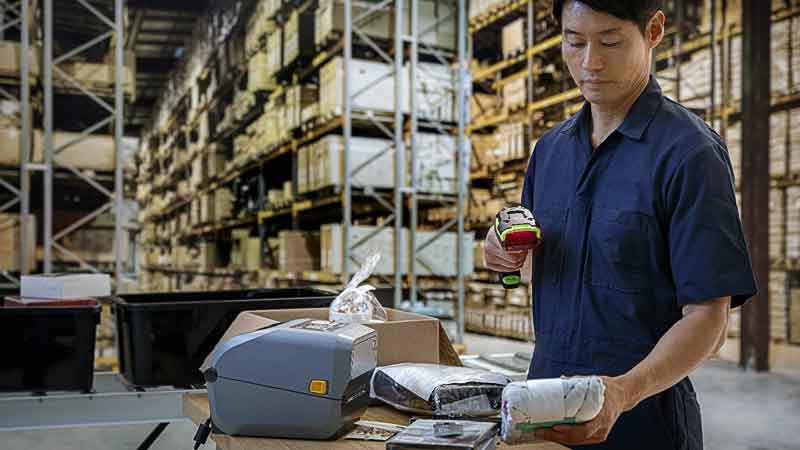 Three Trends Shaping Retail Fulfillment Man Using Zebra Scanner and Zebra Printer on the Desk